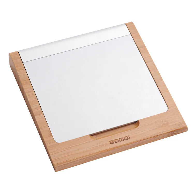Bamboo wood Apple Bluetooth tablet bracket on a desk next to a trackpad.