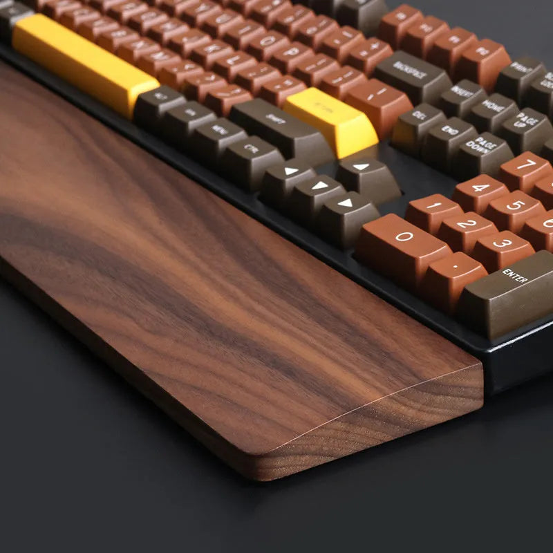 Solid walnut wood keyboard wrist rest with natural grain on a desk
