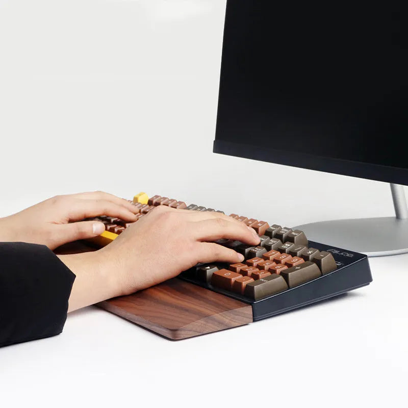 Solid walnut wood keyboard wrist rest with natural grain on a desk