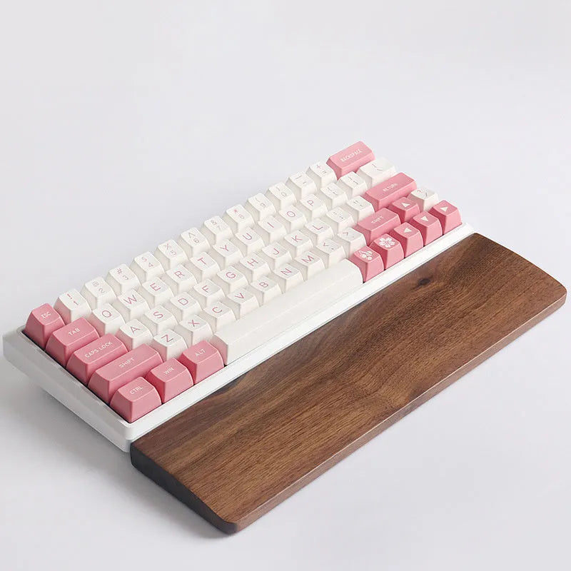 Solid walnut wood keyboard wrist rest with natural grain on a desk