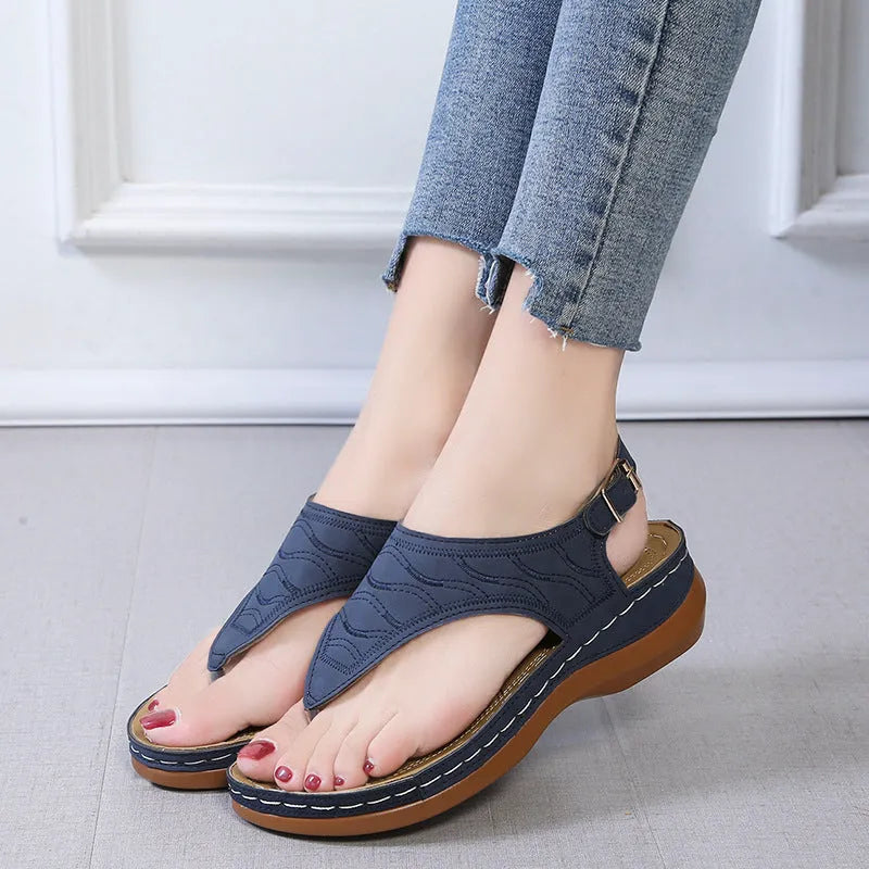 Women's casual wedge heel flip flop sandals with an adjustable buckle strap on the back, shown in a solid colour.