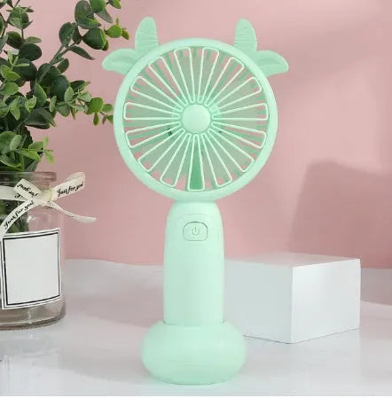 A cartoon-style handheld personal fan with plastic blades, shown in blue, green, pink, and yellow colour options.