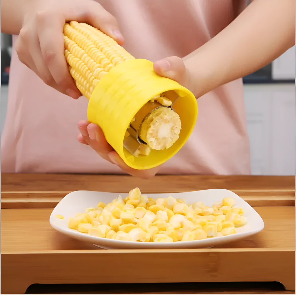 Yellow manual corn grinder thresher with corn-shaped PP handle on a kitchen worktop.