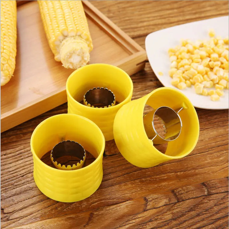 Yellow manual corn grinder thresher with corn-shaped PP handle on a kitchen worktop.