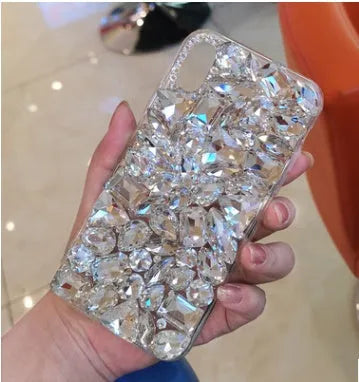 Clear rhinestone crystal decorative phone case for iPhone on a table.