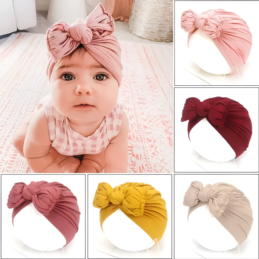 Soft pink knitted acrylic baby bonnet headwrap for a newborn infant.