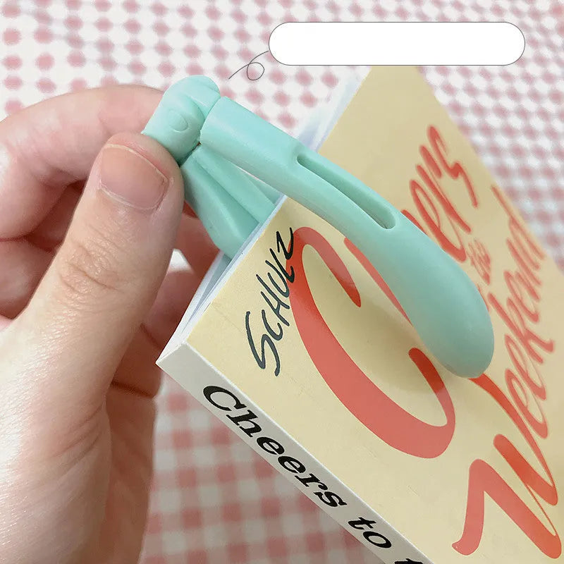 A folded book light in one of four colours: yellow, green, blue, or pink, showing its compact design.