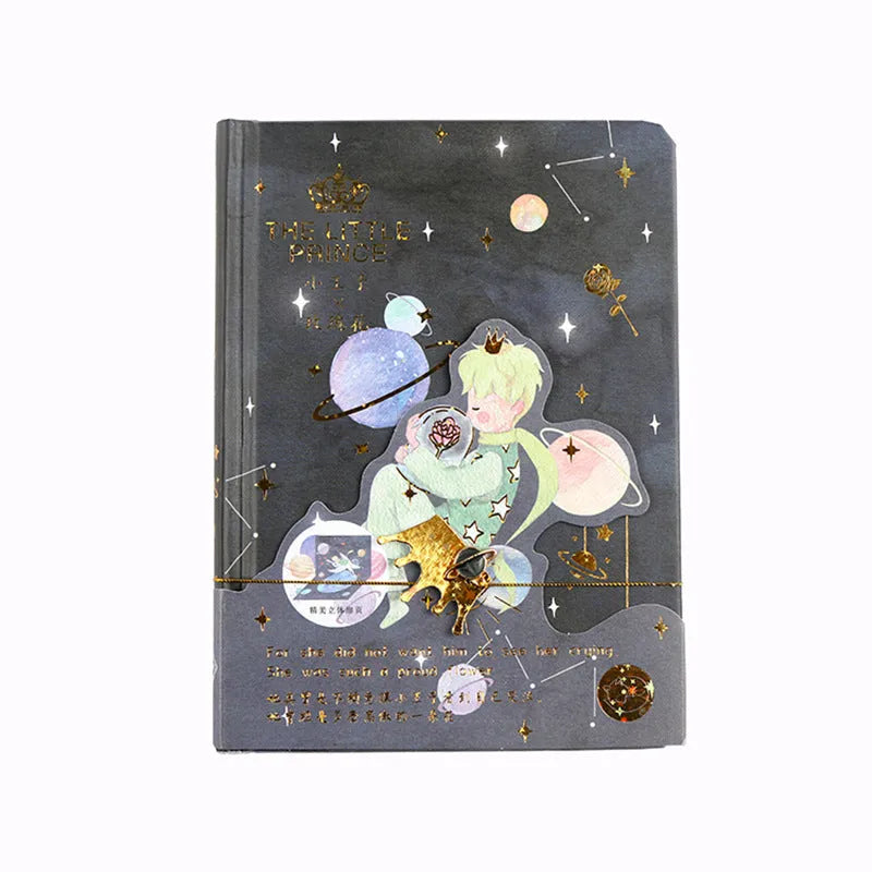 A5 hardback notebook with The Little Prince cartoon illustration cover, open on a flat surface.