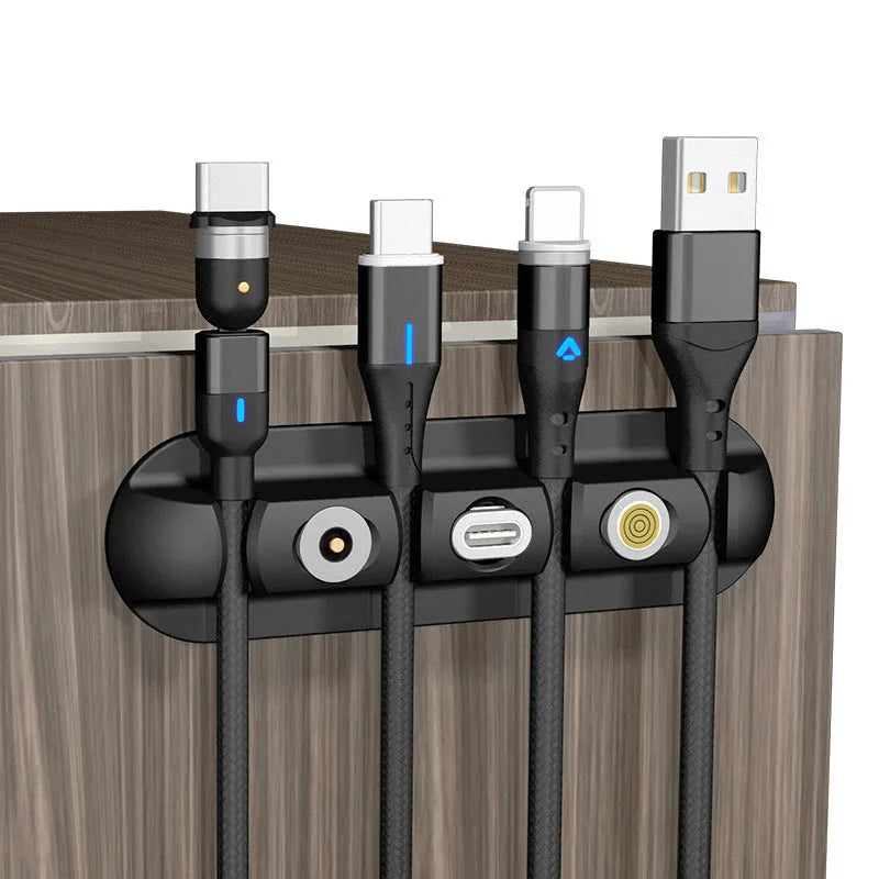 Black soft plastic desktop magnetic data cable organiser on a desk