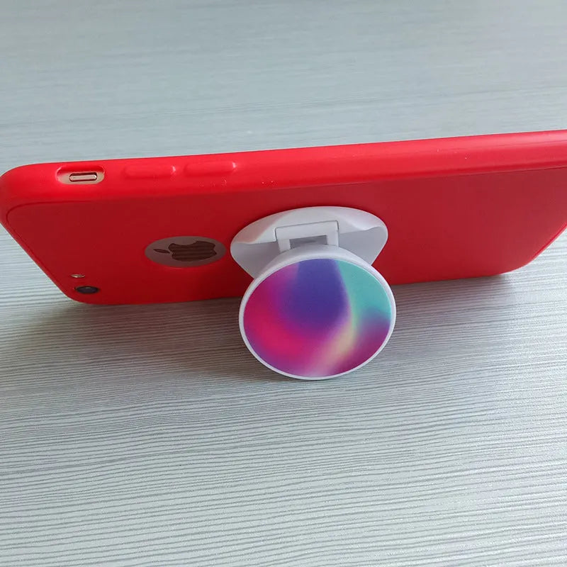 Universal folding mobile phone holder in a choice of colours on a desktop.