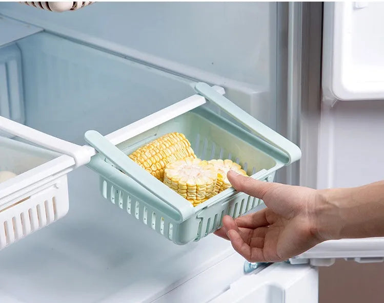 Blue telescopic refrigerator storage basket with adjustable width from 22cm to 34cm on a kitchen counter