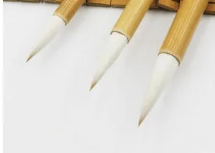 Three traditional Chinese calligraphy brushes with woolen hair tips and bamboo handles in large, medium, and small sizes