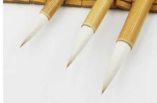 Three traditional Chinese calligraphy brushes with woolen hair tips and bamboo handles in large, medium, and small sizes