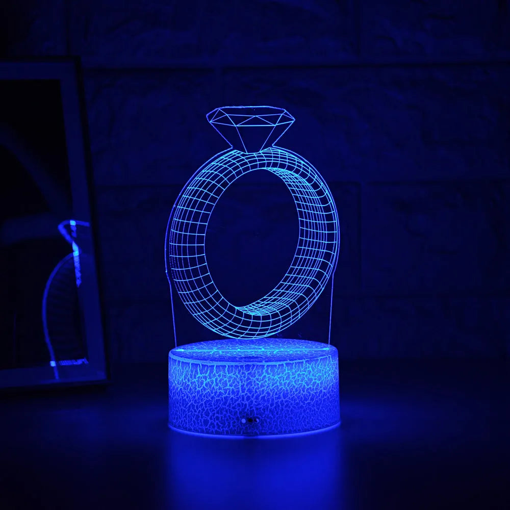 3D LED night light projecting diamond ring design with colour-changing illumination on bedside table