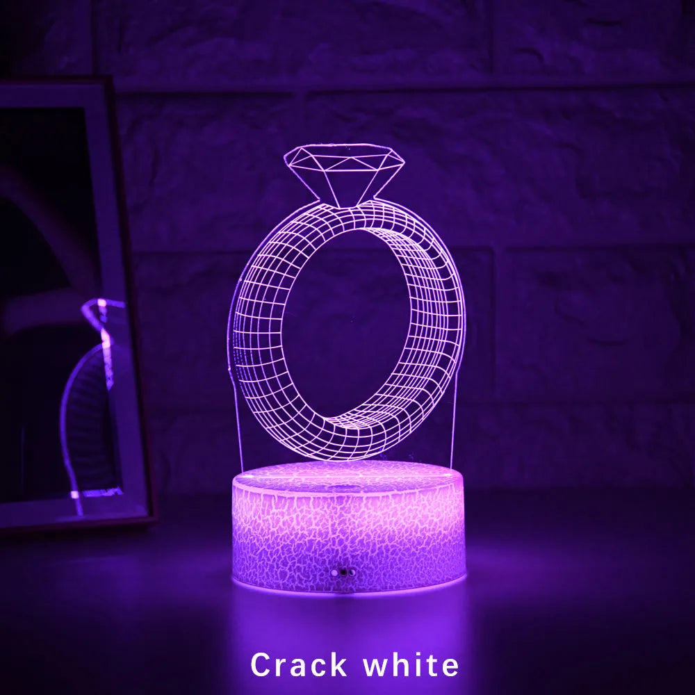3D LED night light projecting diamond ring design with colour-changing illumination on bedside table