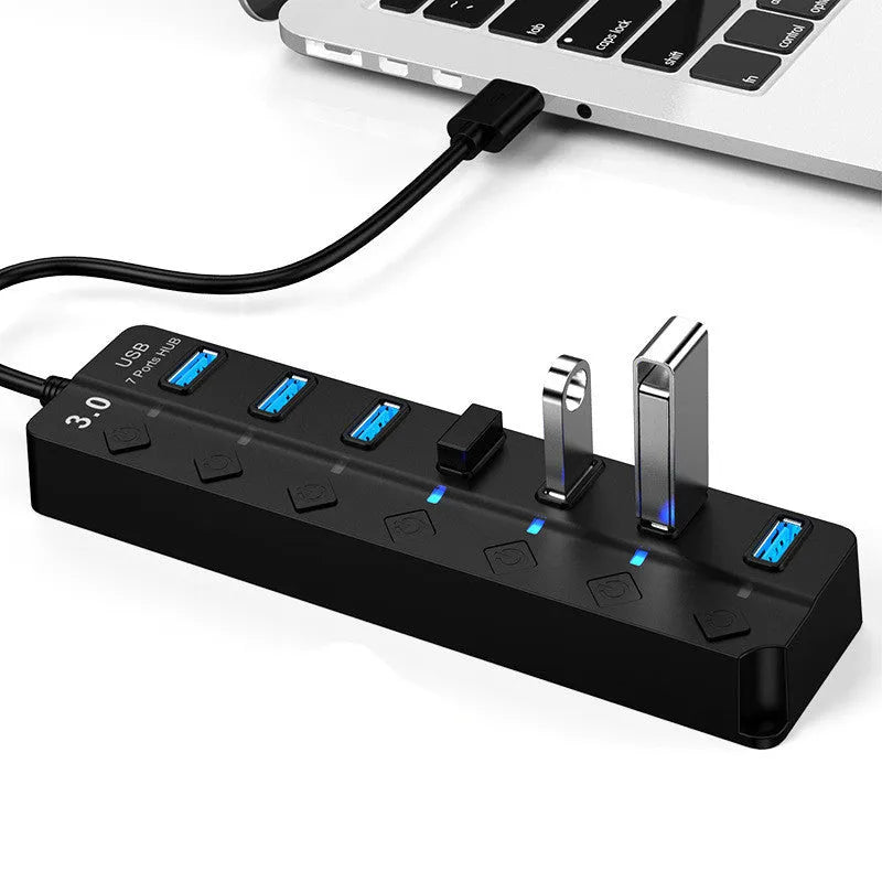 Black 7-port USB 3.0 hub with external power adapter on desk