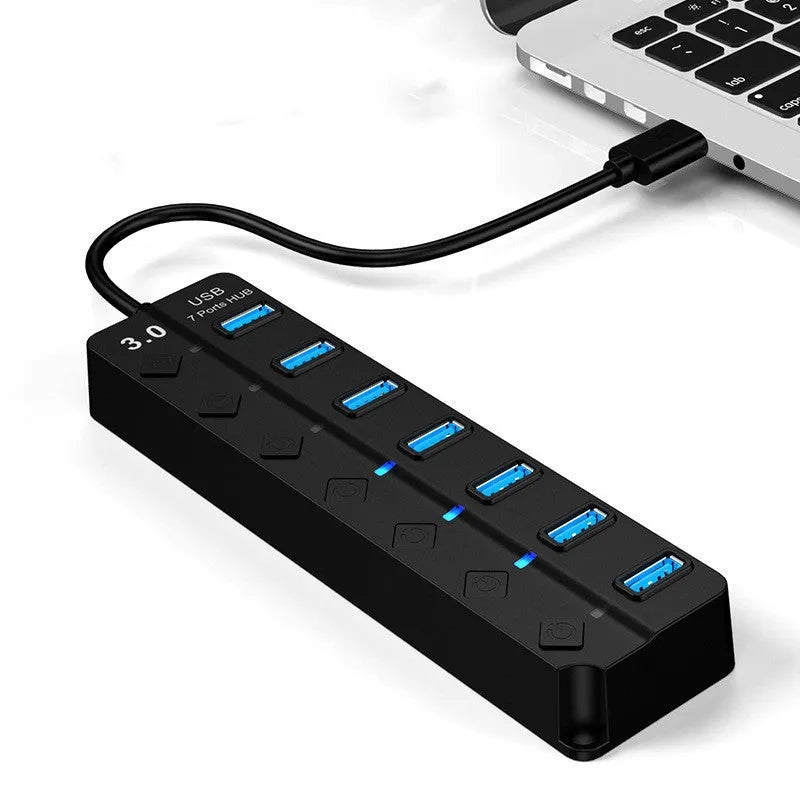Black 7-port USB 3.0 hub with external power adapter on desk