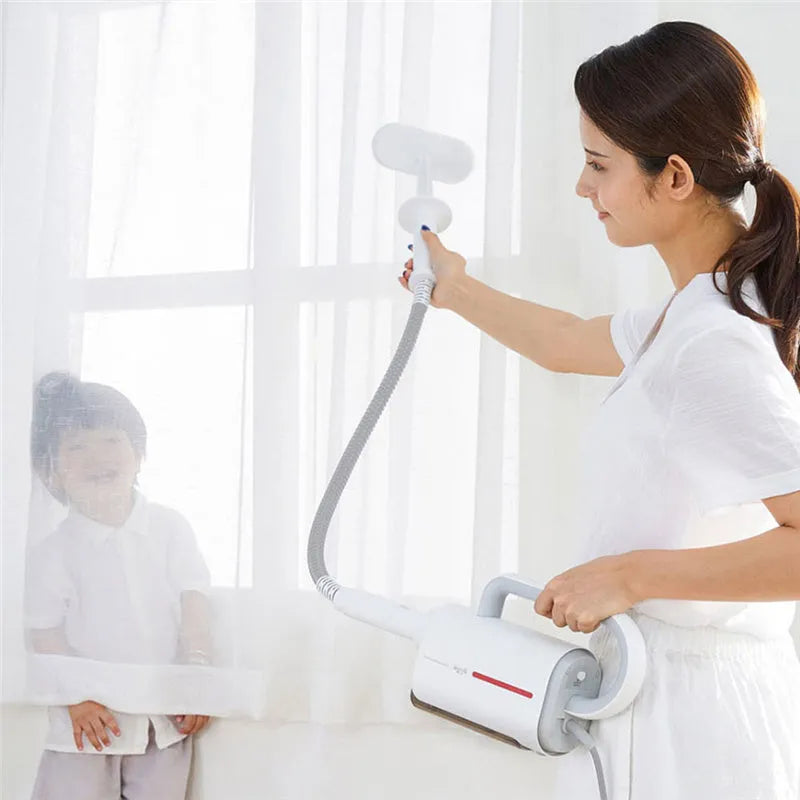 White Deerma DEM-ZQ610 steam cleaner main unit with brush heads and attachments on a table.