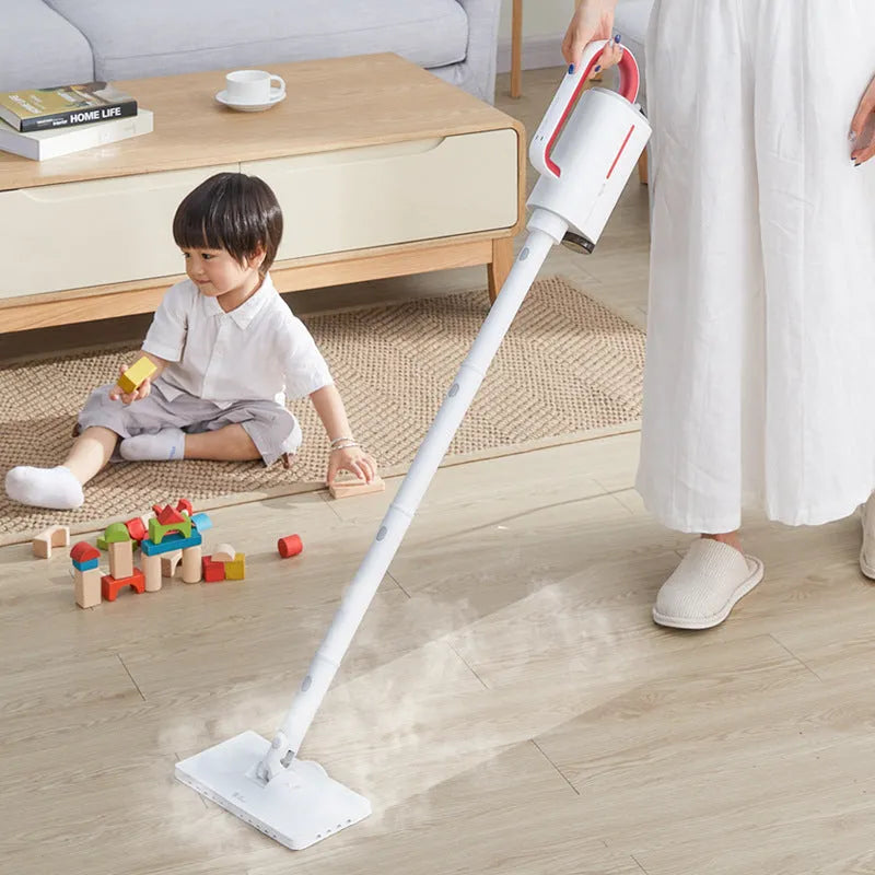 White Deerma DEM-ZQ610 steam cleaner main unit with brush heads and attachments on a table.