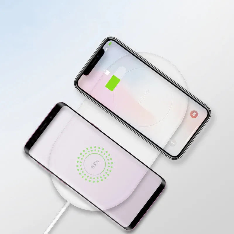 White dual wireless charger charging two mobile phones on a minimalist pad