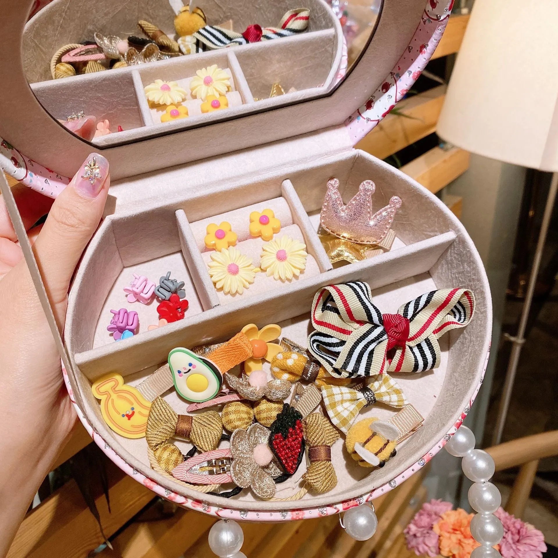 A gift box open to show an assortment of colourful cloth cartoon character hair clips for children.