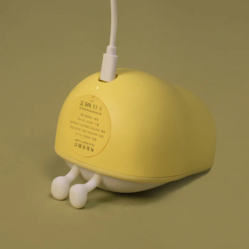 Yellow silicone pear-shaped rechargeable LED night light on a surface