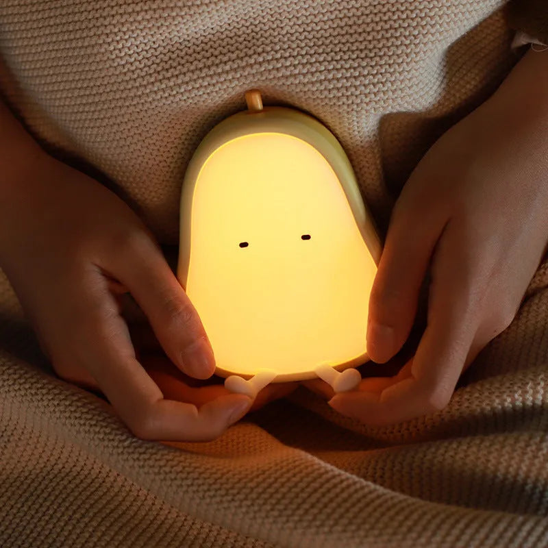 Yellow silicone pear-shaped rechargeable LED night light on a surface