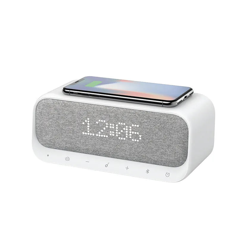 Anker Soundcore white Bluetooth speaker alarm clock with wireless charging pad on a bedside table.