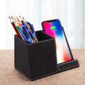 Black leather pen holder wireless charger on desk with phone charging and pens stored