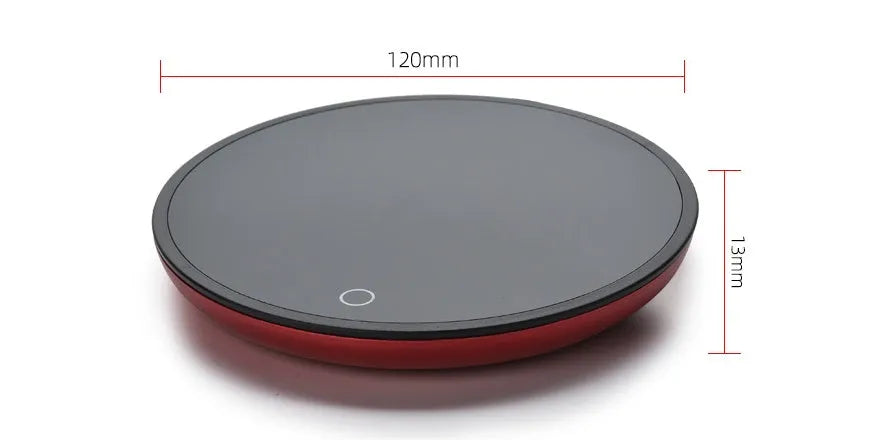 Black coffee cup warmer pad with temperature switch on a desk next to a mug.