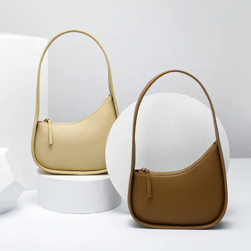 Leather ladies handbag in half-moon shape with wide shoulder strap and zipper opening