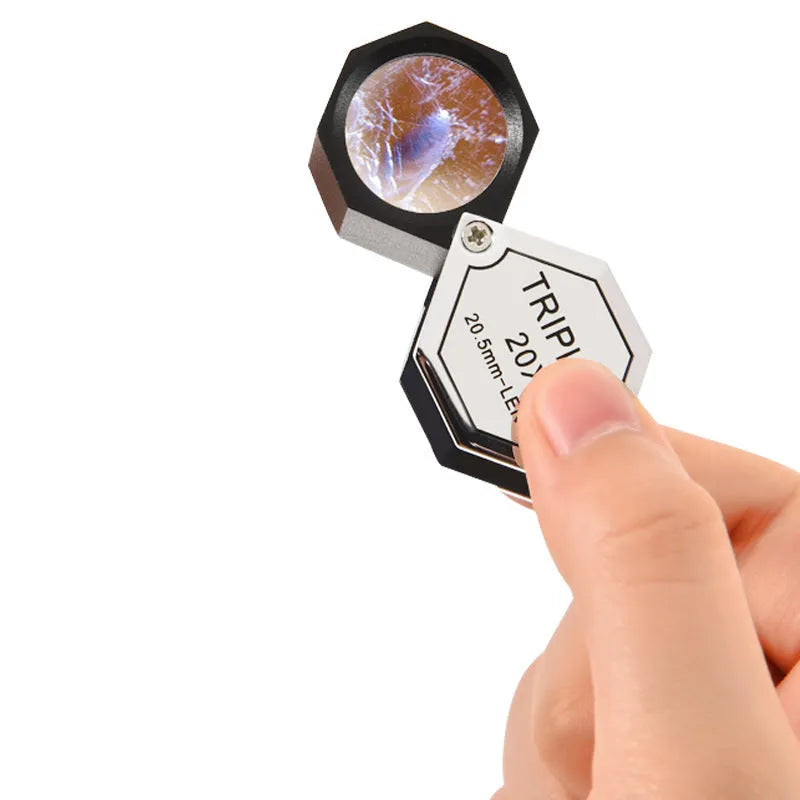 Handheld metal and optical glass magnifying loupe for jewellery and coin inspection.
