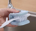 Blue U-shaped plastic brush for cleaning kitchen knives and cutlery on a kitchen counter.