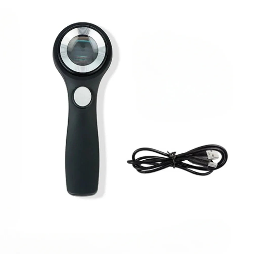 Black and silver jewellery appraisal magnifying glass with optical glass lens and USB-C cable on a table.
