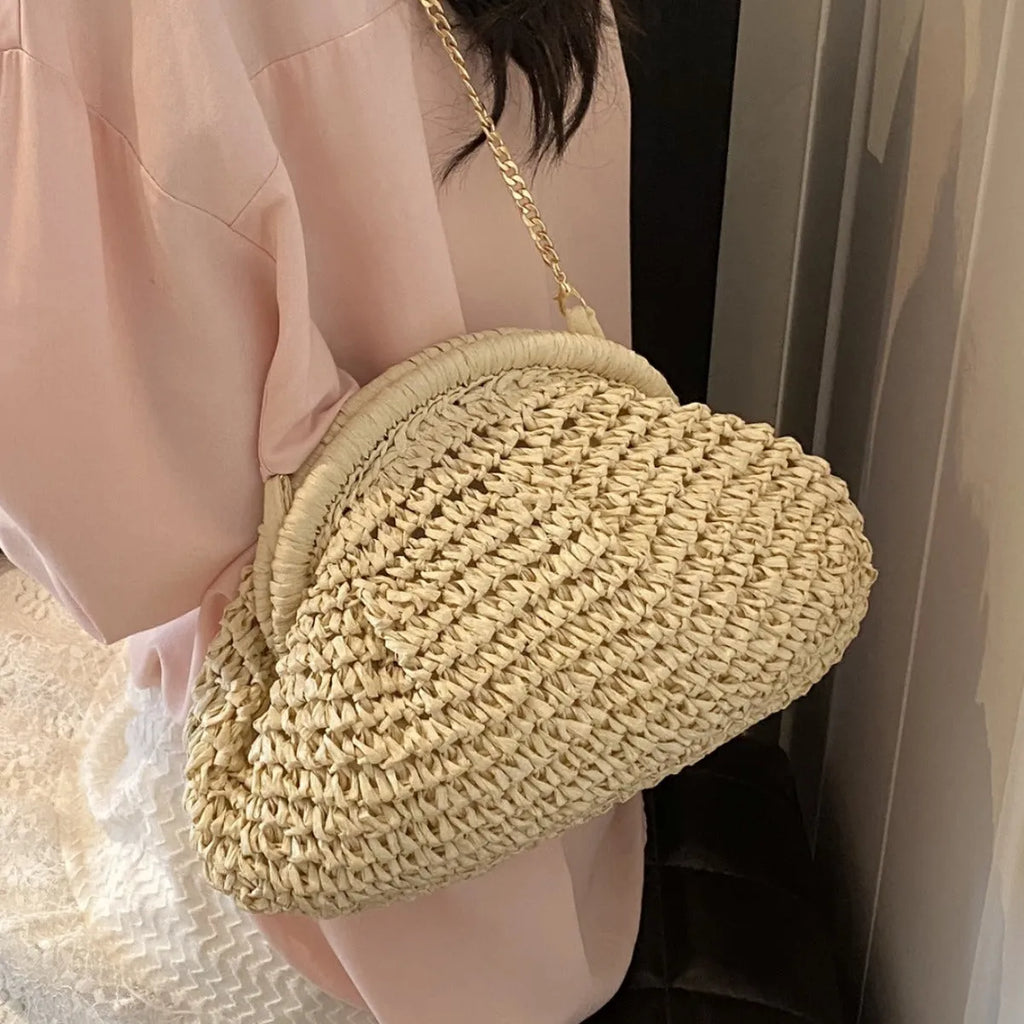 Women's khaki paper straw shoulder bag with a chain strap and shell shape.