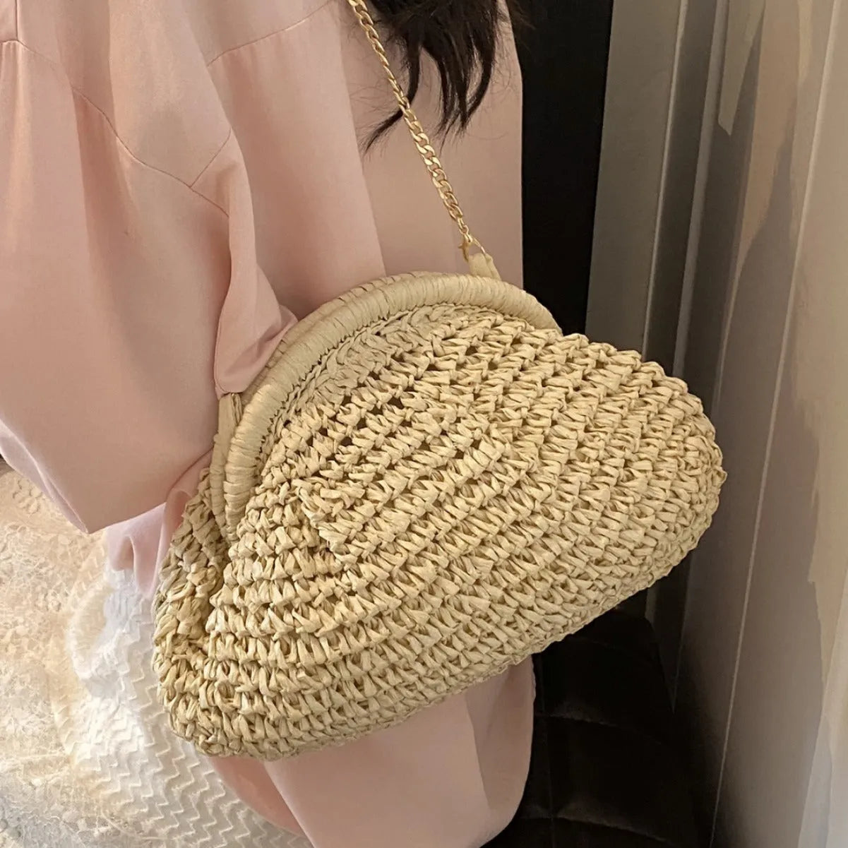Women's khaki paper straw shoulder bag with a chain strap and shell shape.