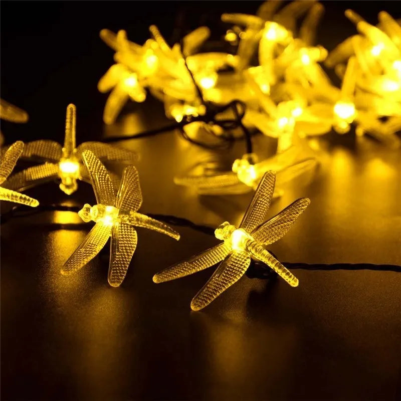 5-metre long solar-powered dragonfly string lights with warm white LEDs and a ground-spike solar panel for outdoor use.