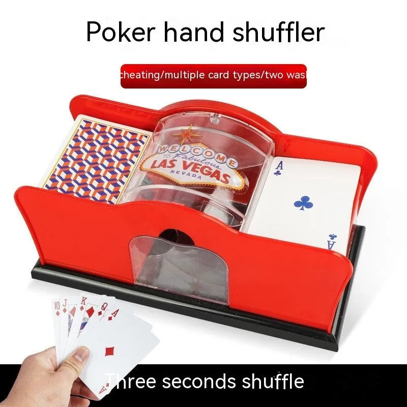 Black manual card shuffler with hand crank on a table next to playing cards.