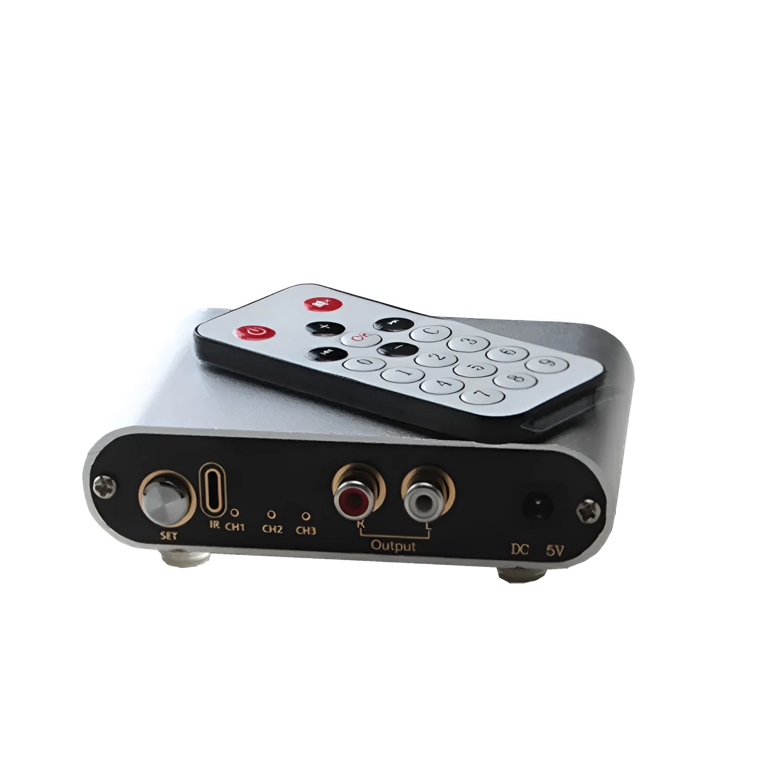 Silver aluminium alloy audio source switcher unit with front-panel switch button and infrared remote control.