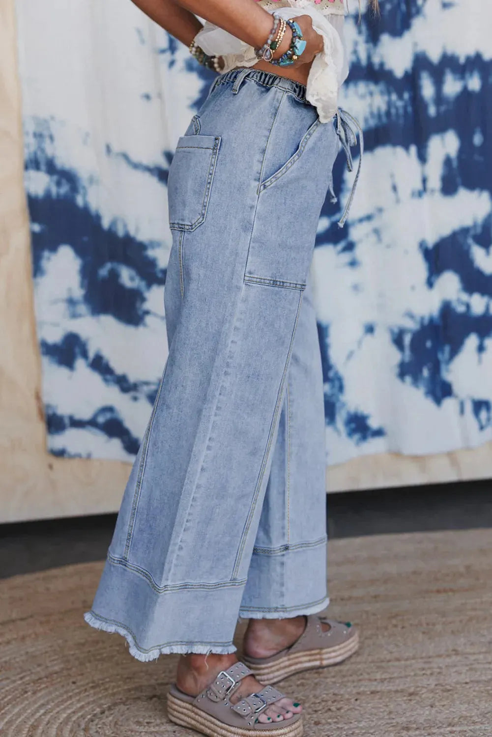 Beau blue wide leg denim pants with drawstring waist and raw hem detail laid flat