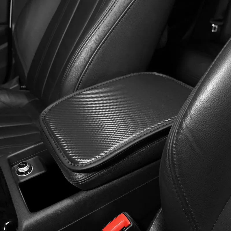 Leather car armrest cushion in black, khaki, red, and white colours, shown on a car centre console.