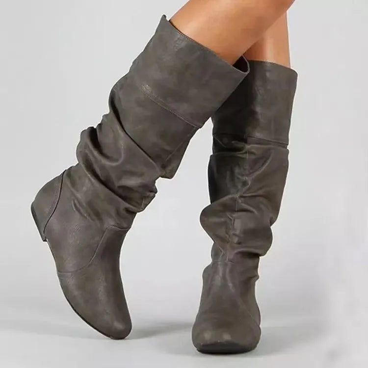 Women's flat heel slip-on boots in black with round toe and high cylinder length, showcasing non-slip rubber sole.