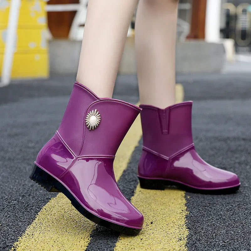 Women's purple PVC rain boots with a middle tube height and non-slip sole on a wet surface.