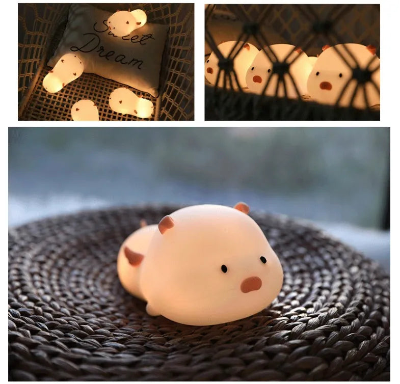 Cute pink silicone pig night light with sleeping design on a bedside table.
