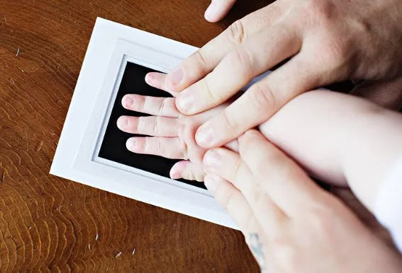 Wash-free baby handprint and footprint ink kit with printing oil, two paper sheets and disposable printing table for 0-6 months.