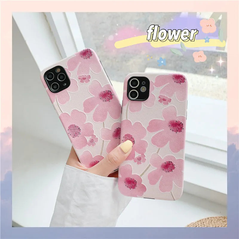 Pink soft rubber flower phone case for iPhone models on a flat surface, showing lanyard hole.