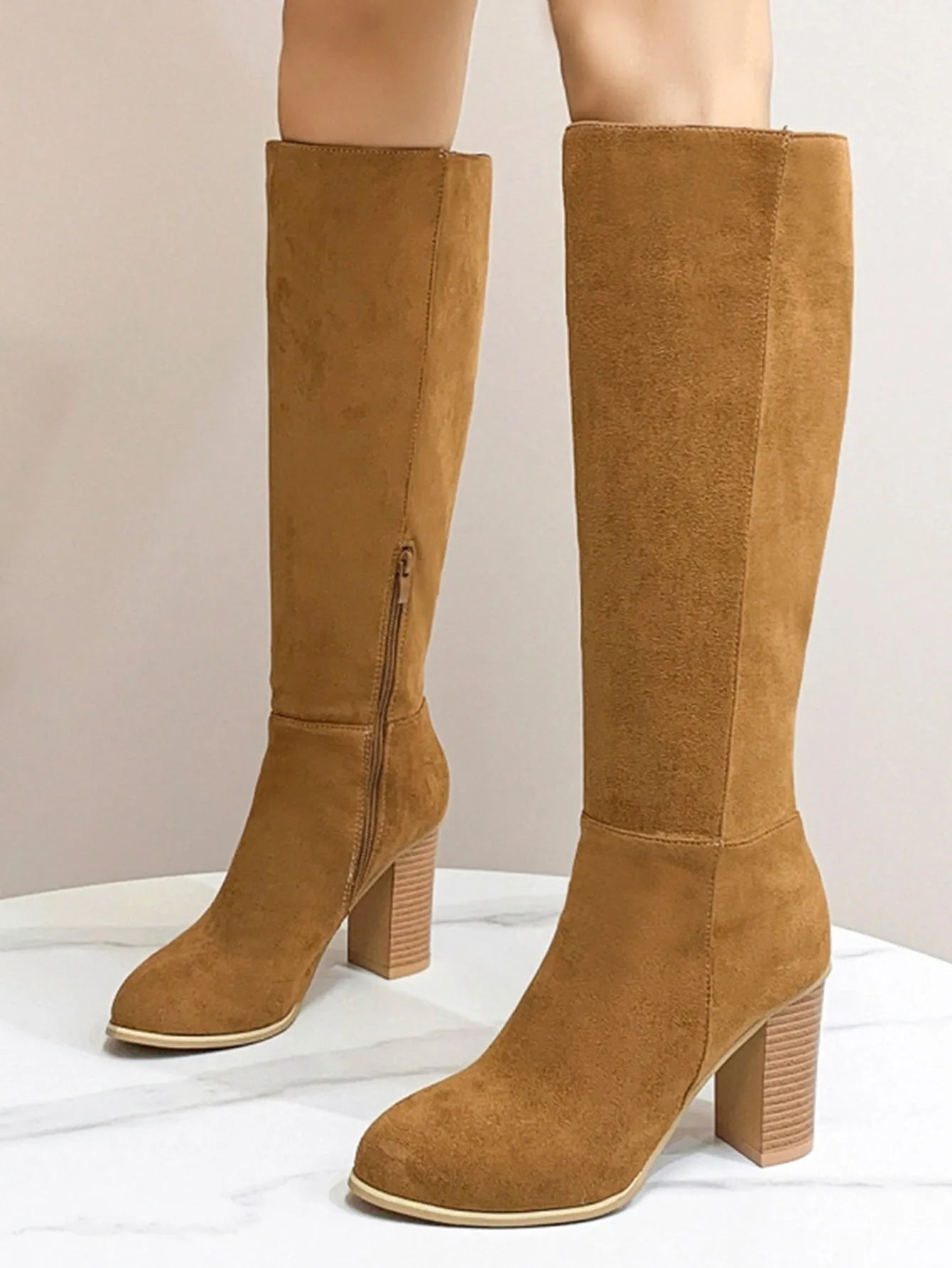 Women's black square toe ankle boots with a block heel on a wooden floor.