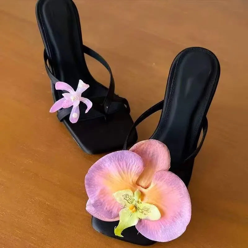 Handmade women's high-heel sandals with square toe and asymmetric floral decoration on calf leather.