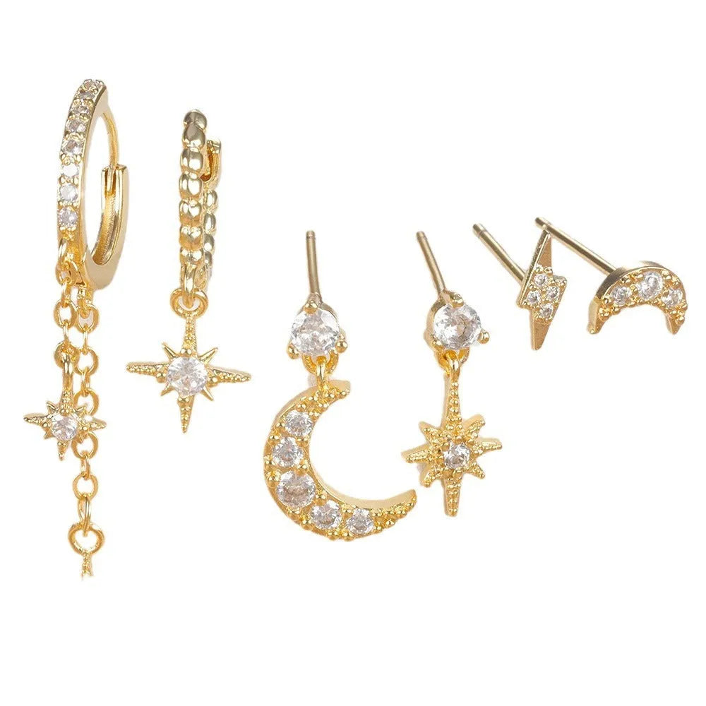 XINGX set of six gold chain tassel and zircon stud drop earrings laid out on a dark surface