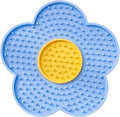 Flower-shaped silicone slow feeder licking mat for dogs and cats with suction cups on a smooth surface.